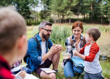 Group of school children with teacher on field trip in nature, learning science.