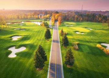 Road through the golf course at sunset in autumn. Aerial view